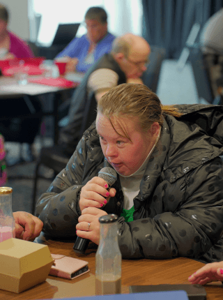 portrait of a woman speaking into a microphone.